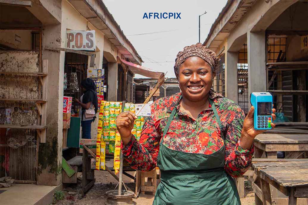 Joyful African Woman Holding ATM Card and POS Outside Her Shop